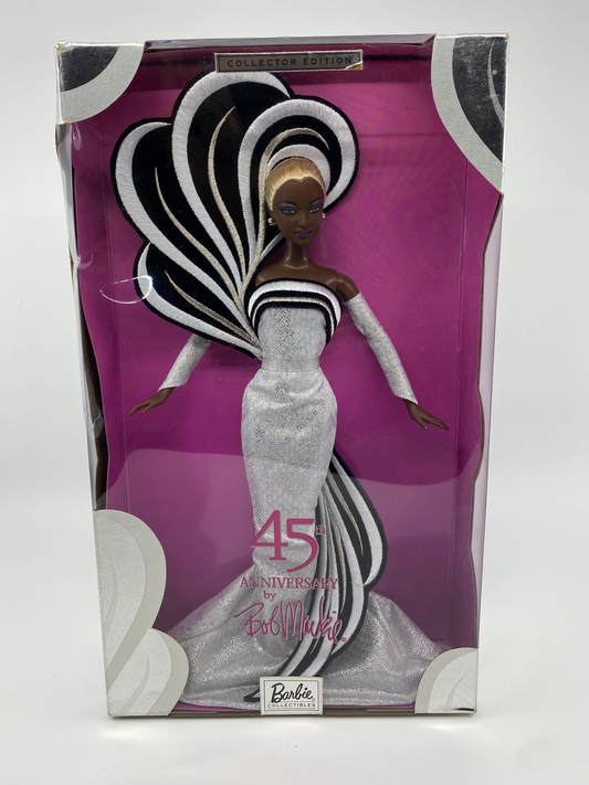 Barbie doll in a silver dress with a purple packaging box featuring a stylized heart design.