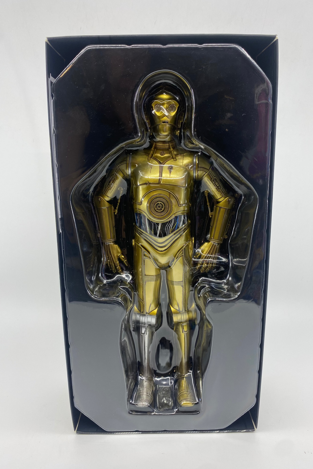 Gold robot figure in clear packaging on a white background