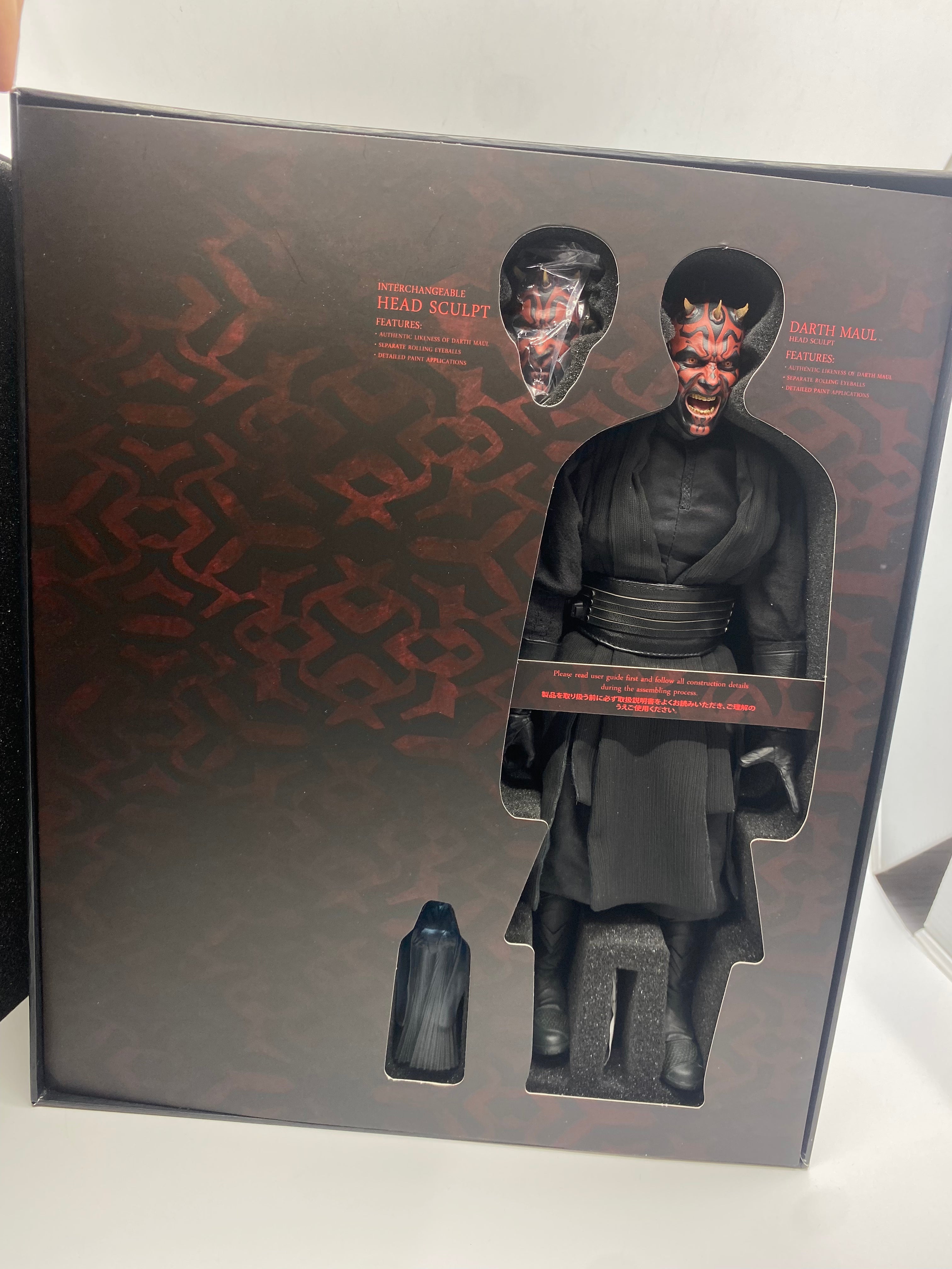 Action figure packaging with a character in a black outfit and helmet on a white surface.