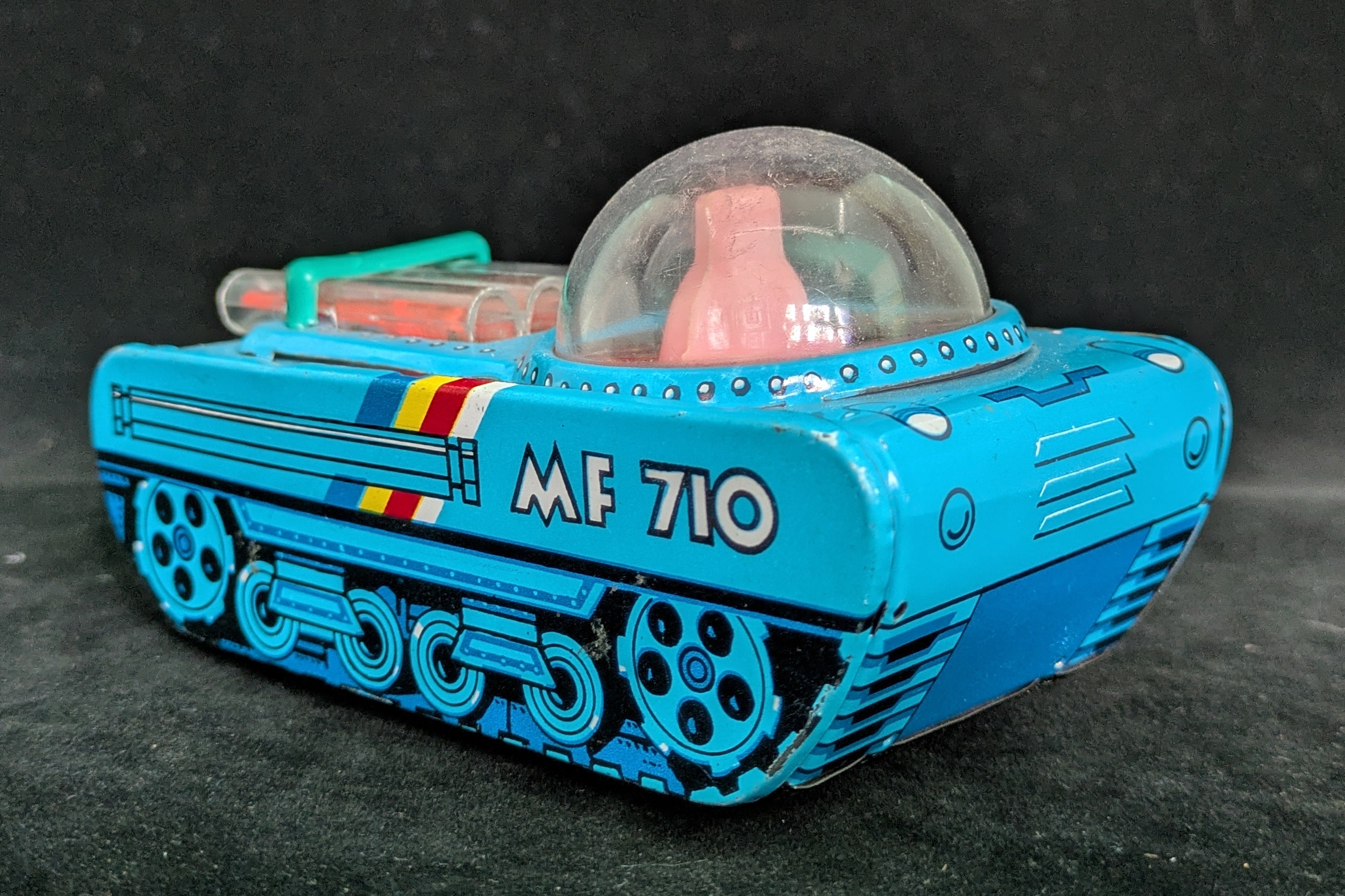 Toy robot with blue body and transparent dome on a dark background