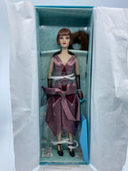 Doll in a box with a purple outfit on a white background