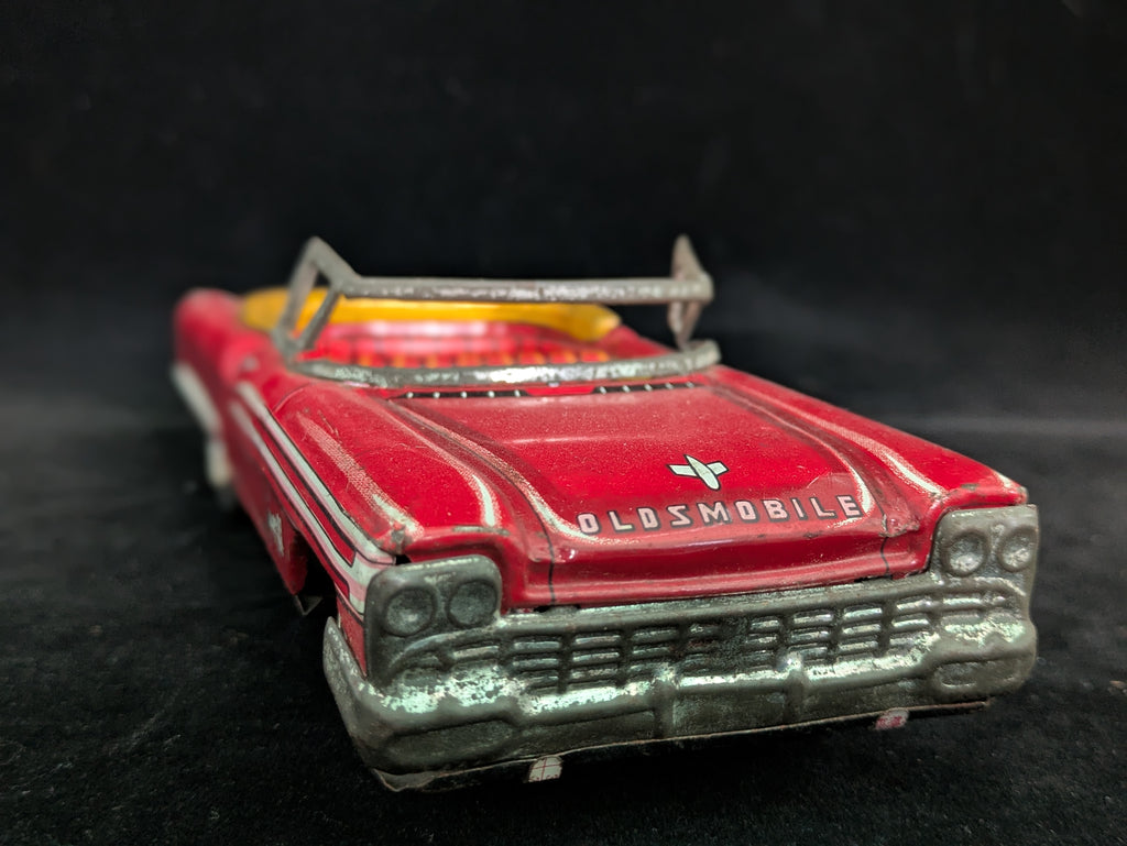 Red toy Oldsmobile car on a black background
