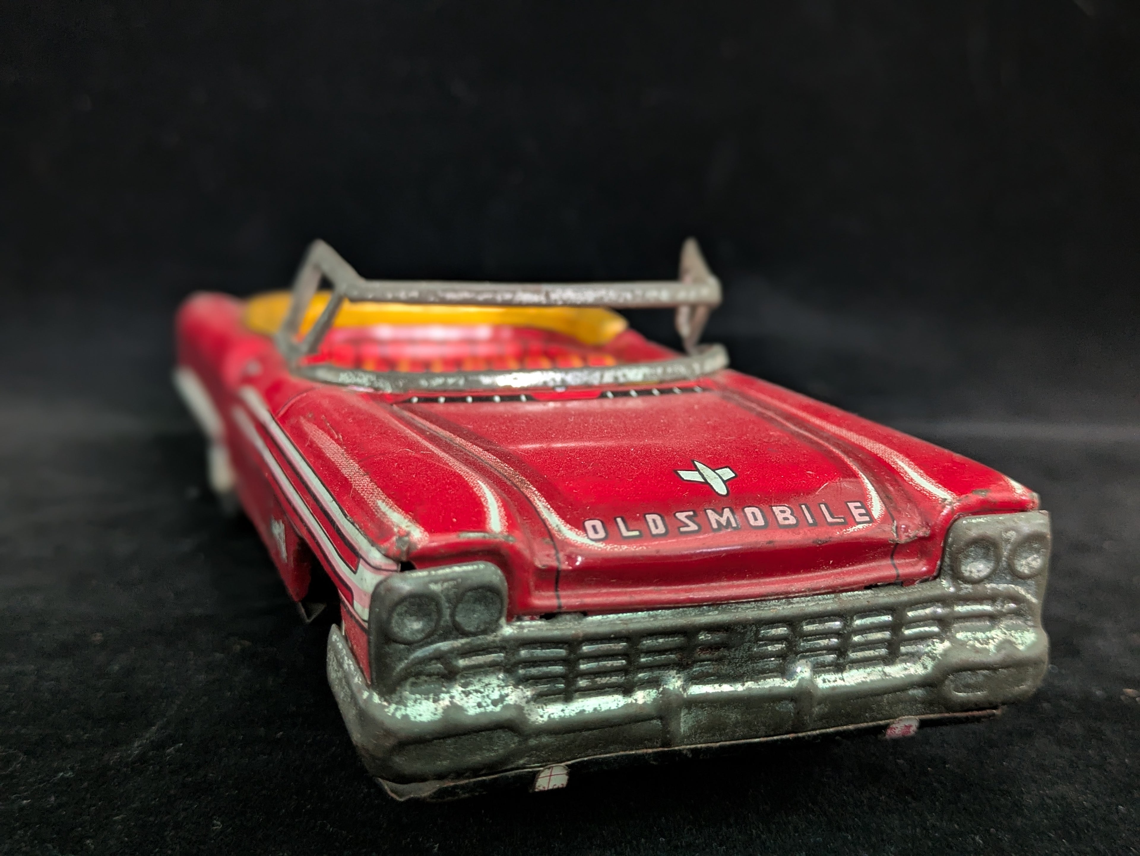 Red toy Oldsmobile car on a black background