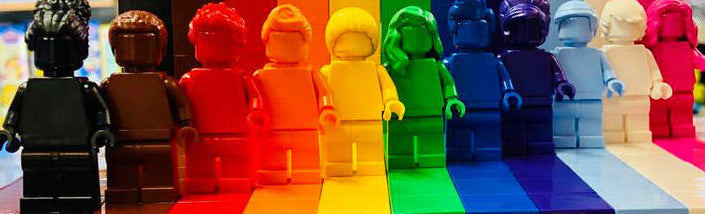 Colorful LEGO figures arranged in a rainbow pattern on a shelf.