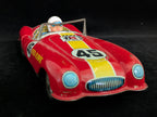 Red toy race car with driver figure on a black background