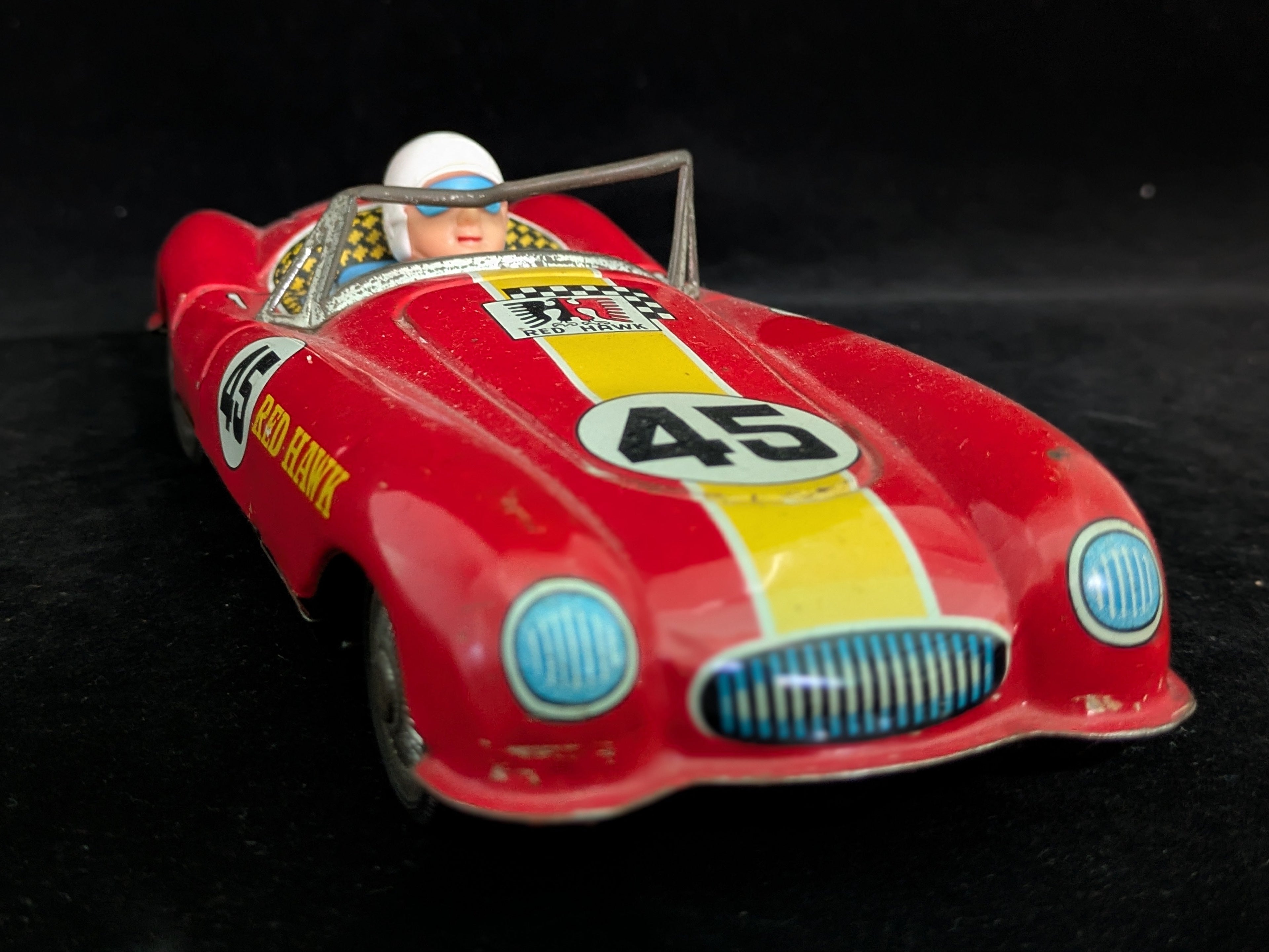 Red toy race car with driver figure on a black background