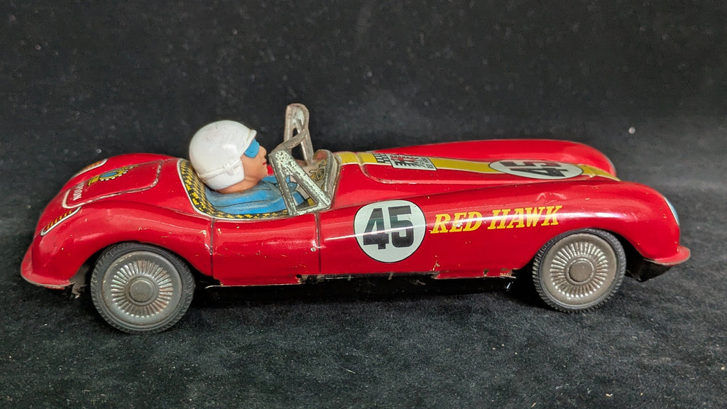 Red toy car with driver figure on a dark background