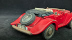 Red vintage toy car with a black roof on a dark background