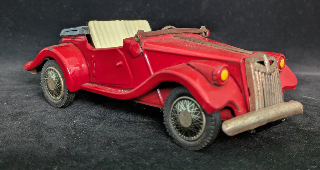 Red vintage toy car on a dark textured surface