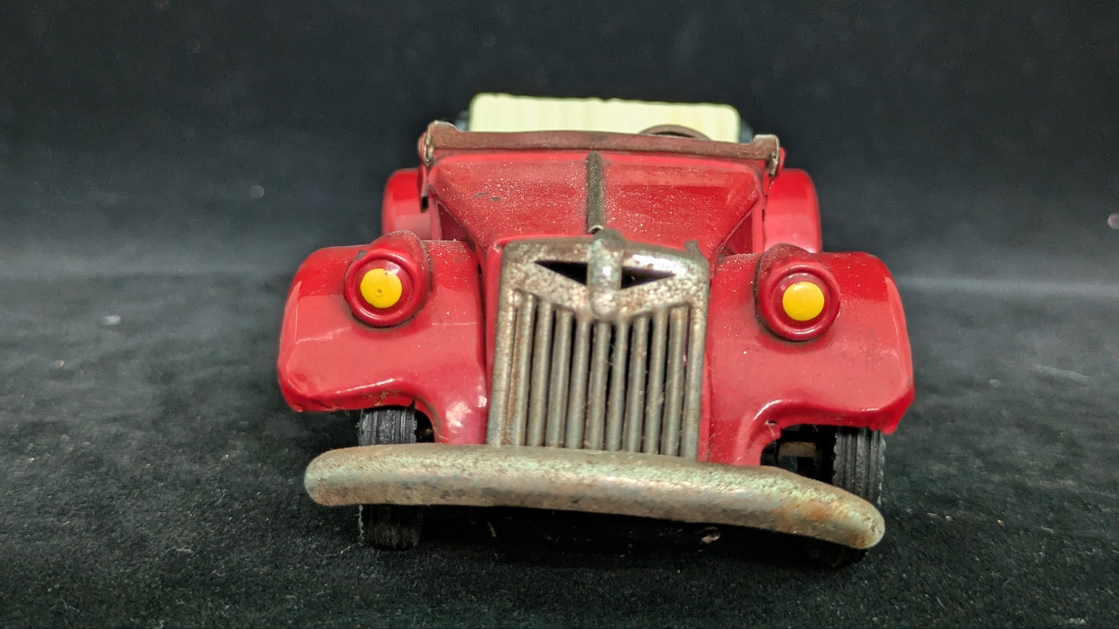Red toy car on a dark textured surface