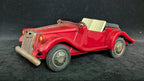 Red vintage toy car on a dark textured surface
