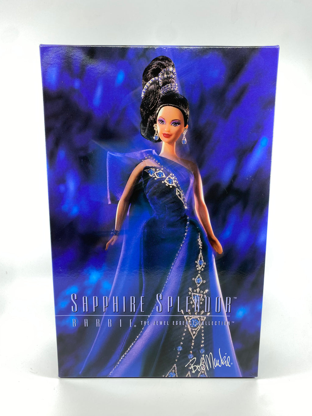 Barbie doll in a blue gown with intricate detailing on a blue and black gradient background