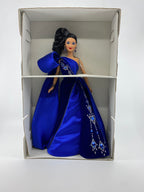 Barbie doll in a blue gown with intricate detailing in a box on a white background