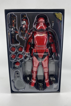 Red and black action figure in packaging on a white background