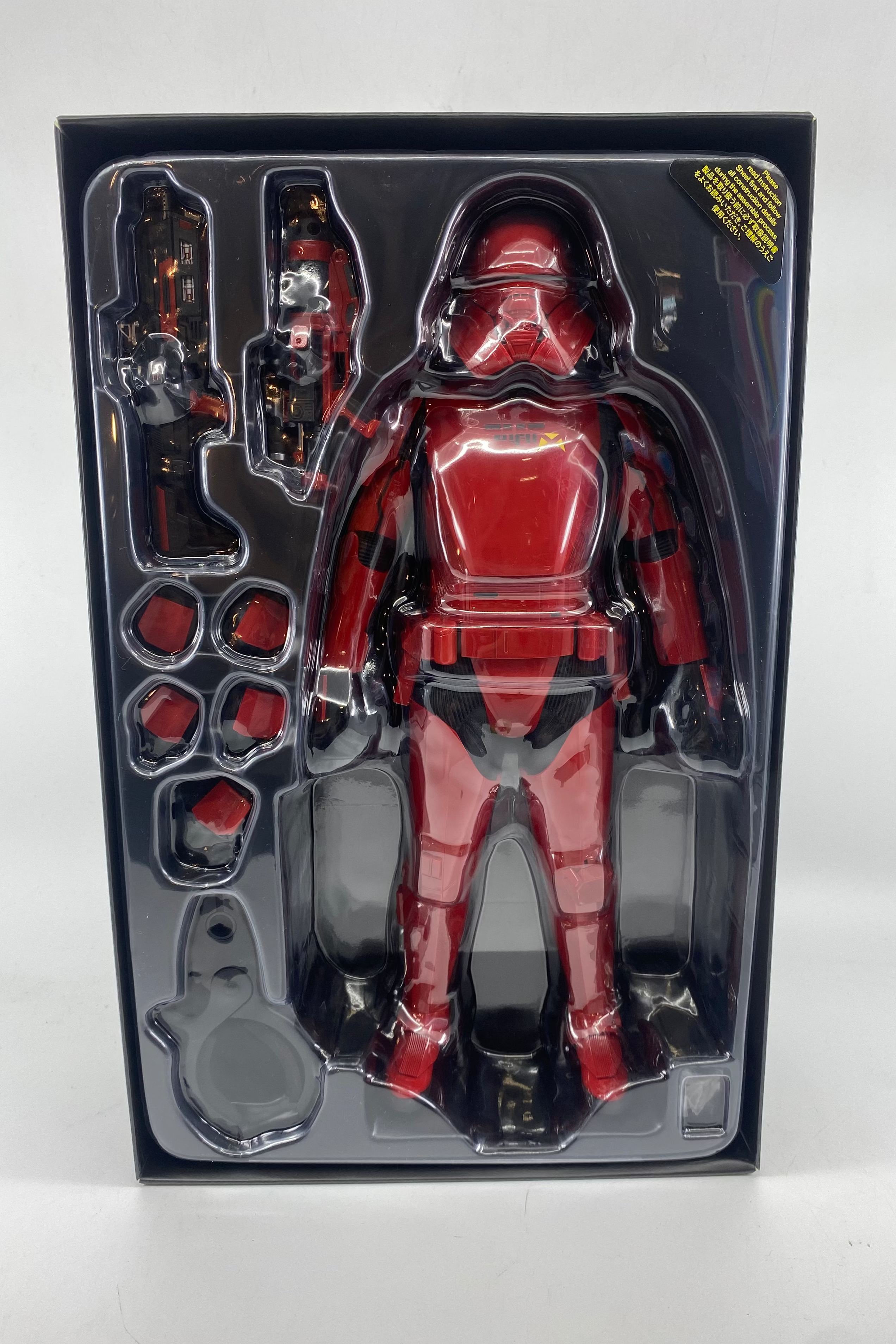 Red and black action figure in packaging on a white background
