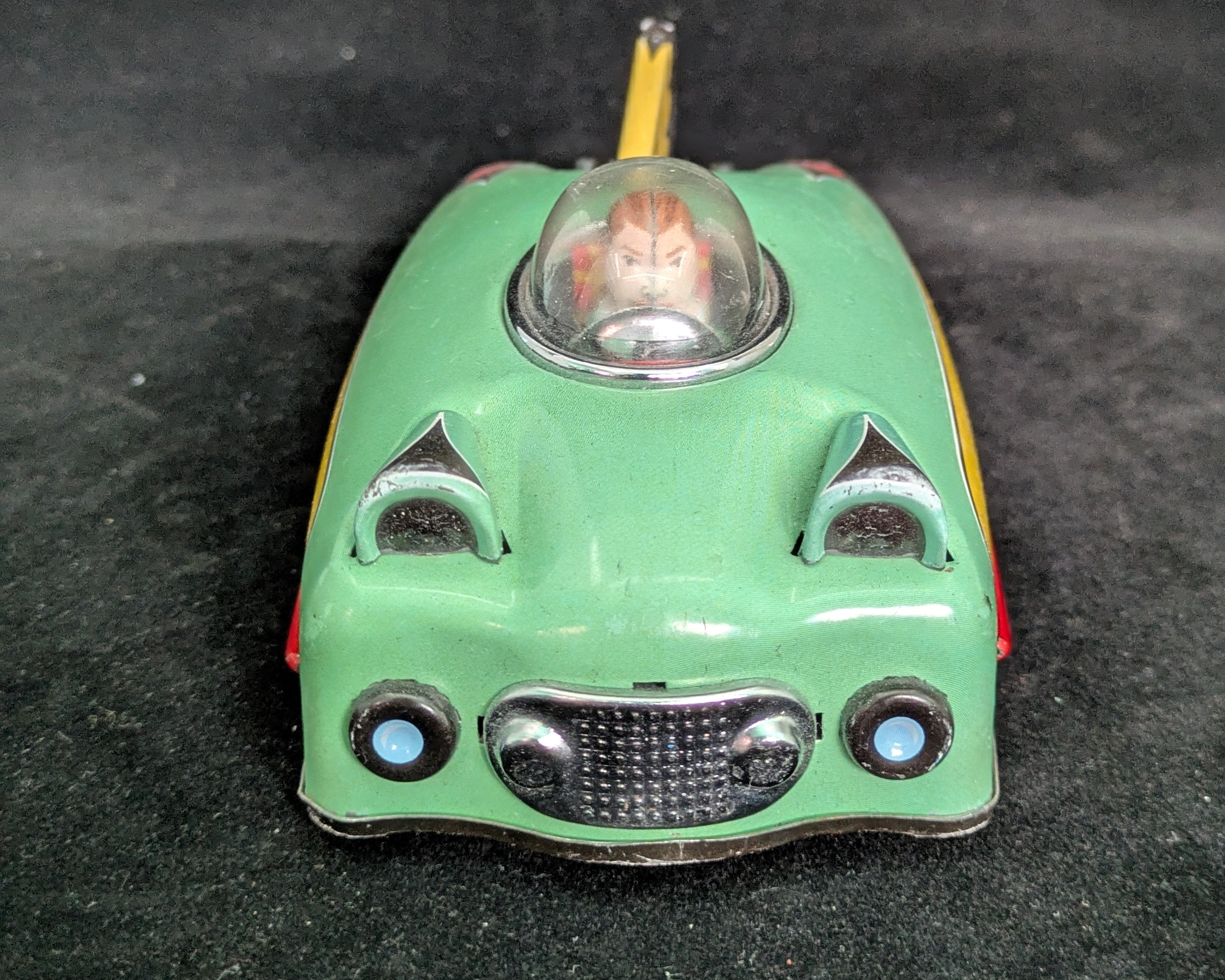 Small green toy car with a clear dome on a dark background