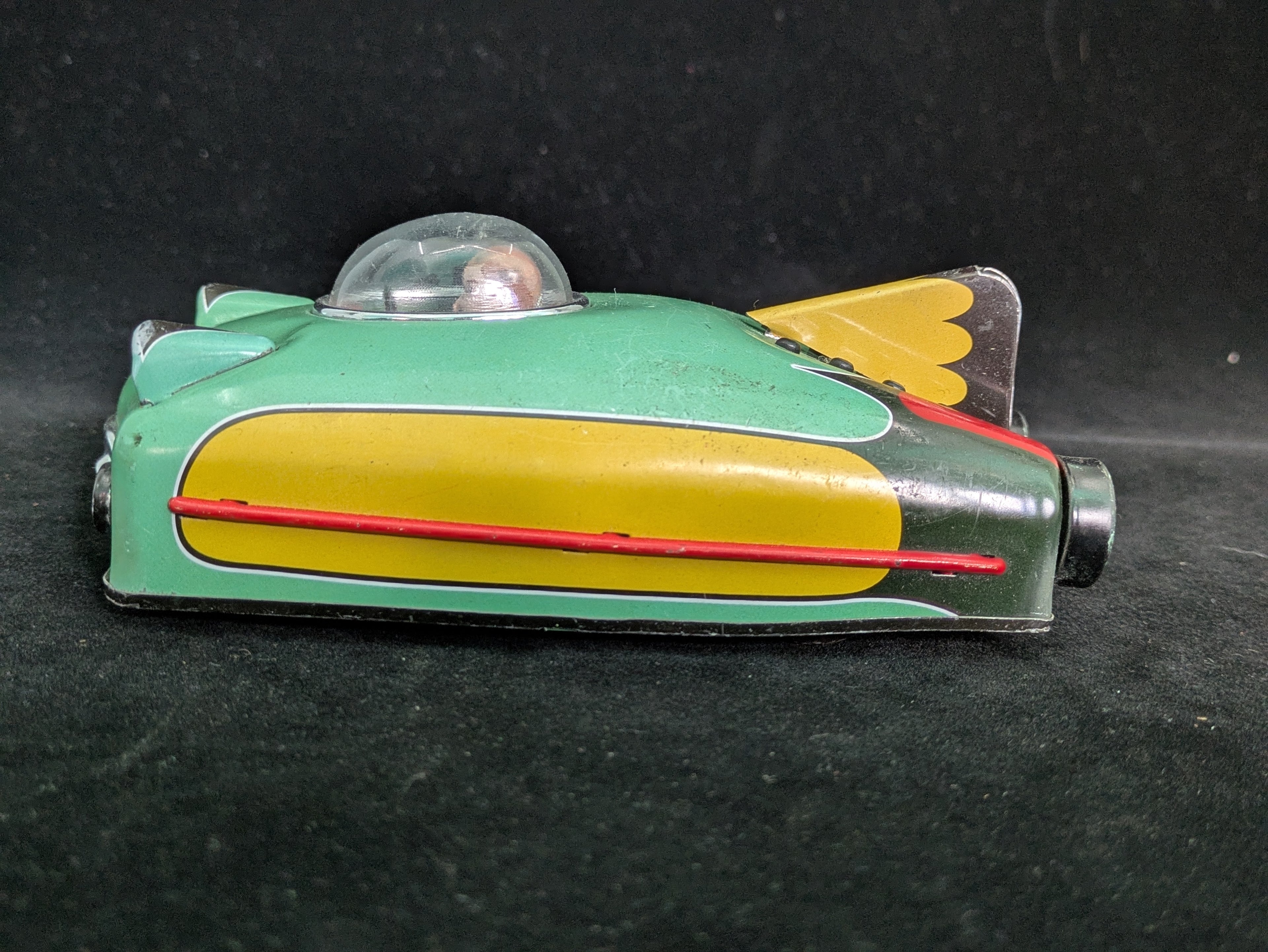 Toy vehicle with green body, yellow wings, and red accents on a black background
