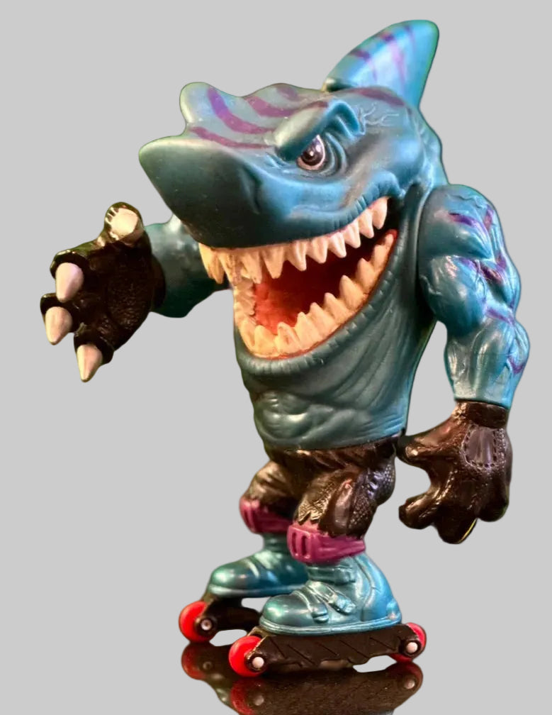 Toy figure of a shark on roller skates with a green blurred background.