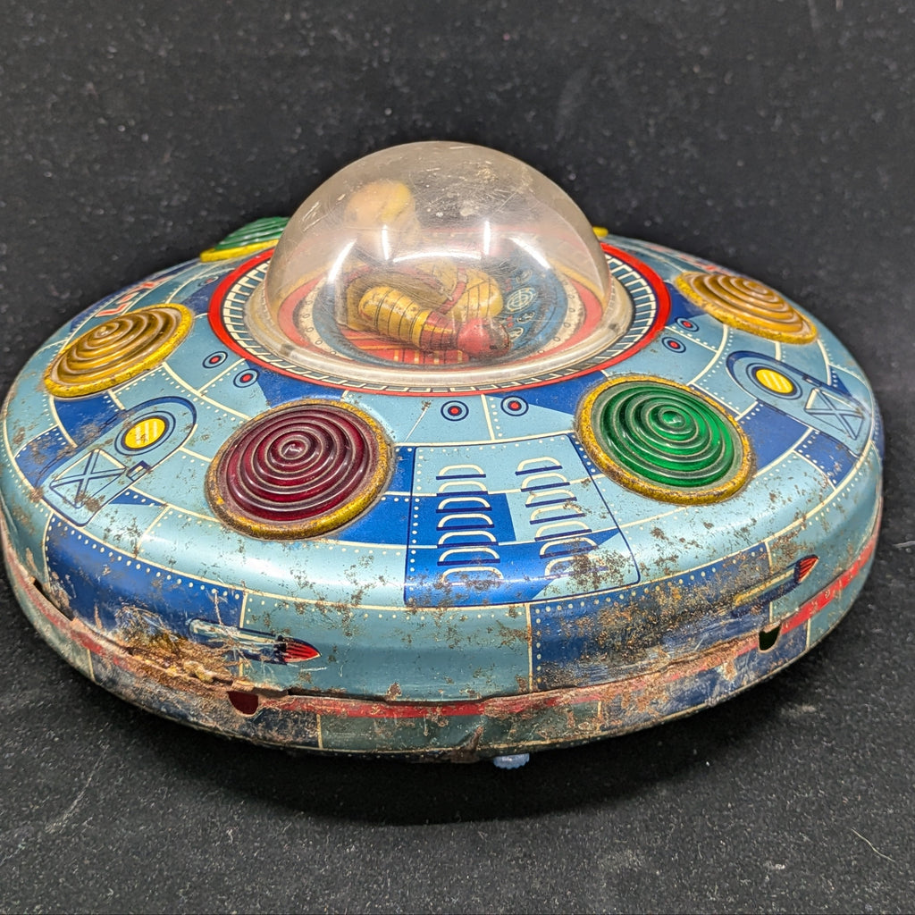 Vintage tin toy UFO with colorful design on a black background