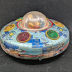 Vintage tin toy UFO with colorful design on a black background