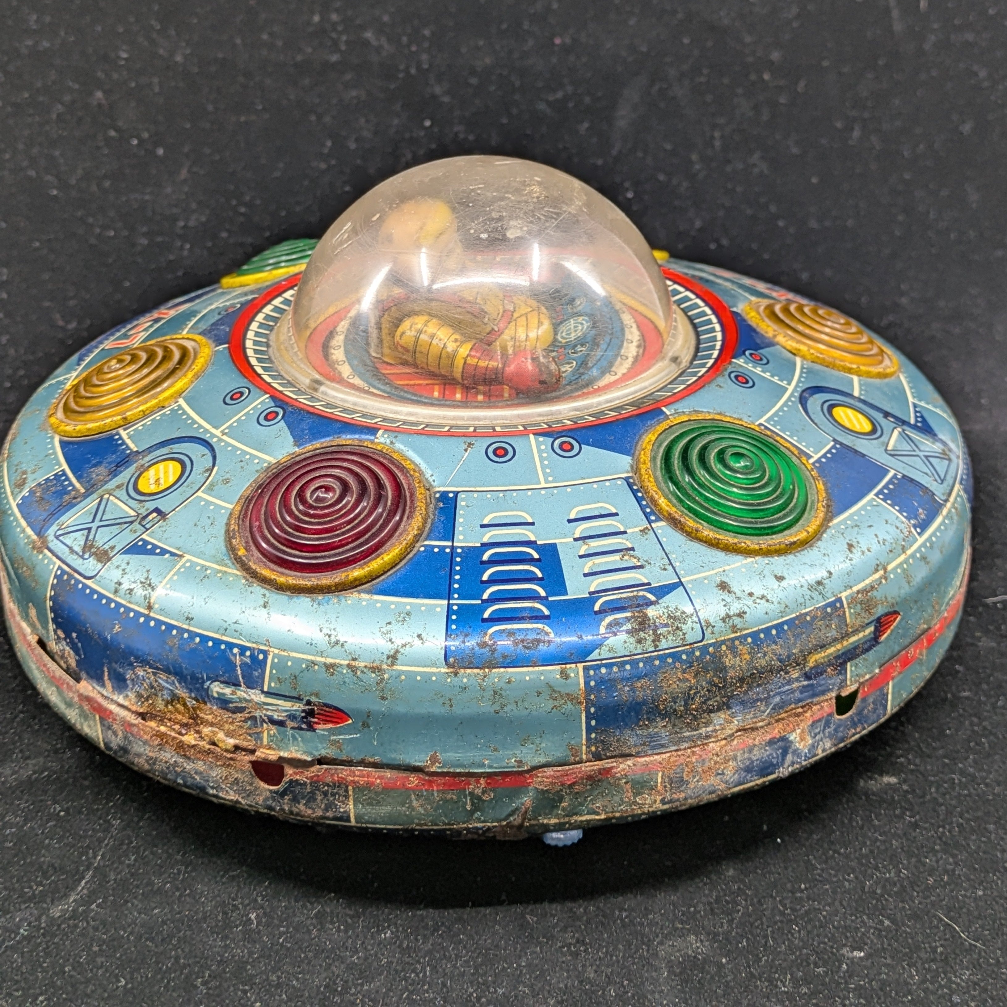 Vintage tin toy UFO with colorful design on a black background
