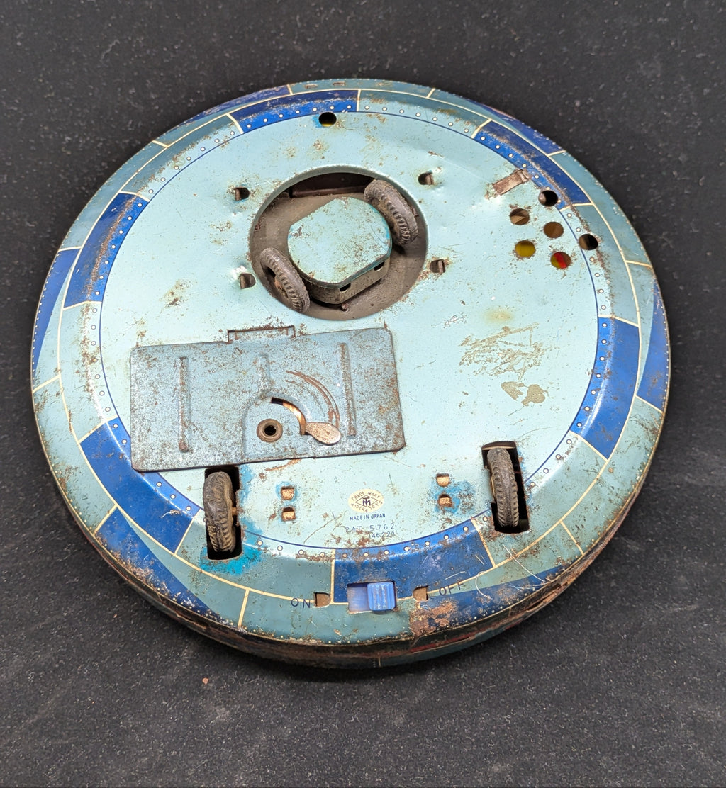 Round metallic component with blue and rust-colored finish on a dark background