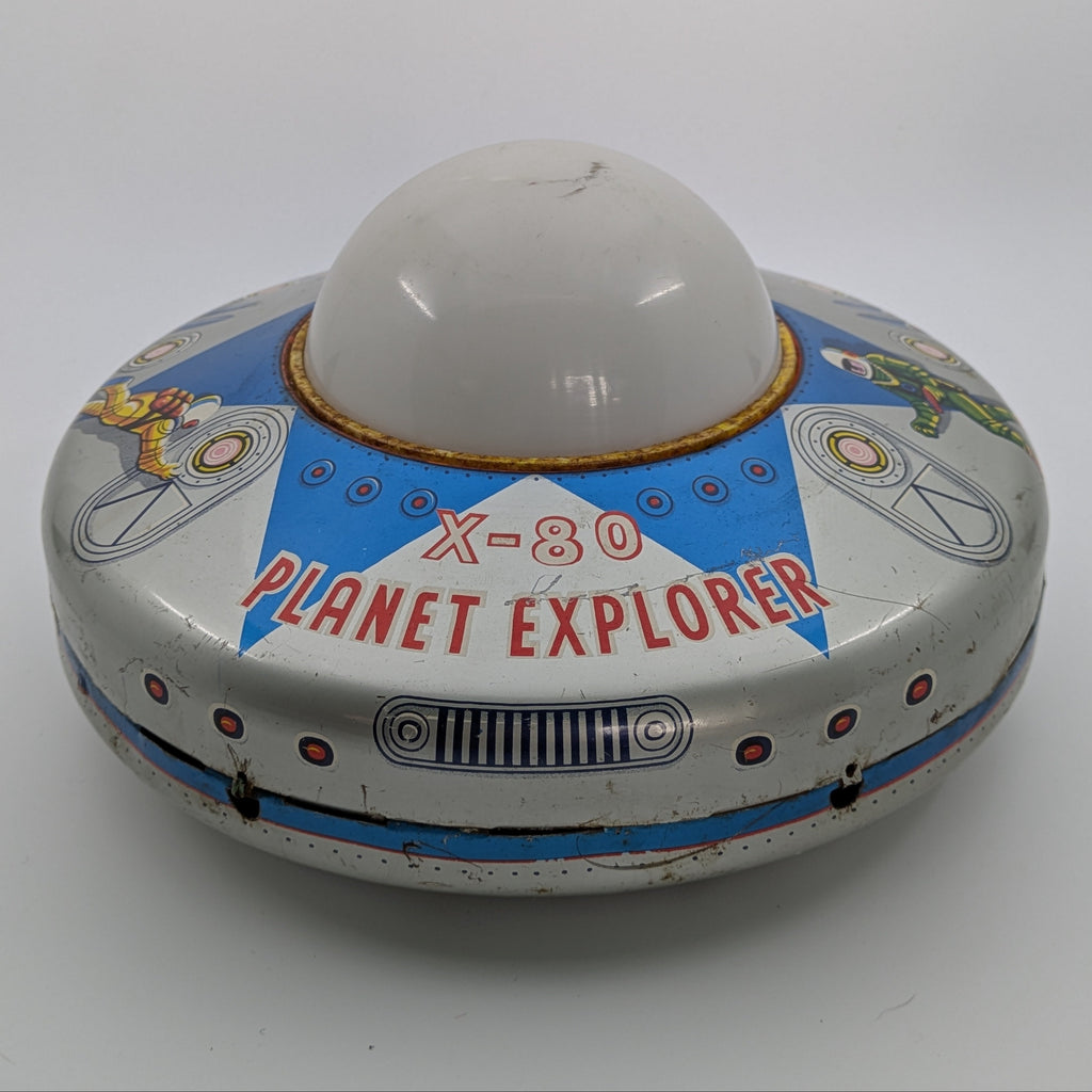 Toy resembling a UFO with 'X-80 Planet Explorer' text on a white background