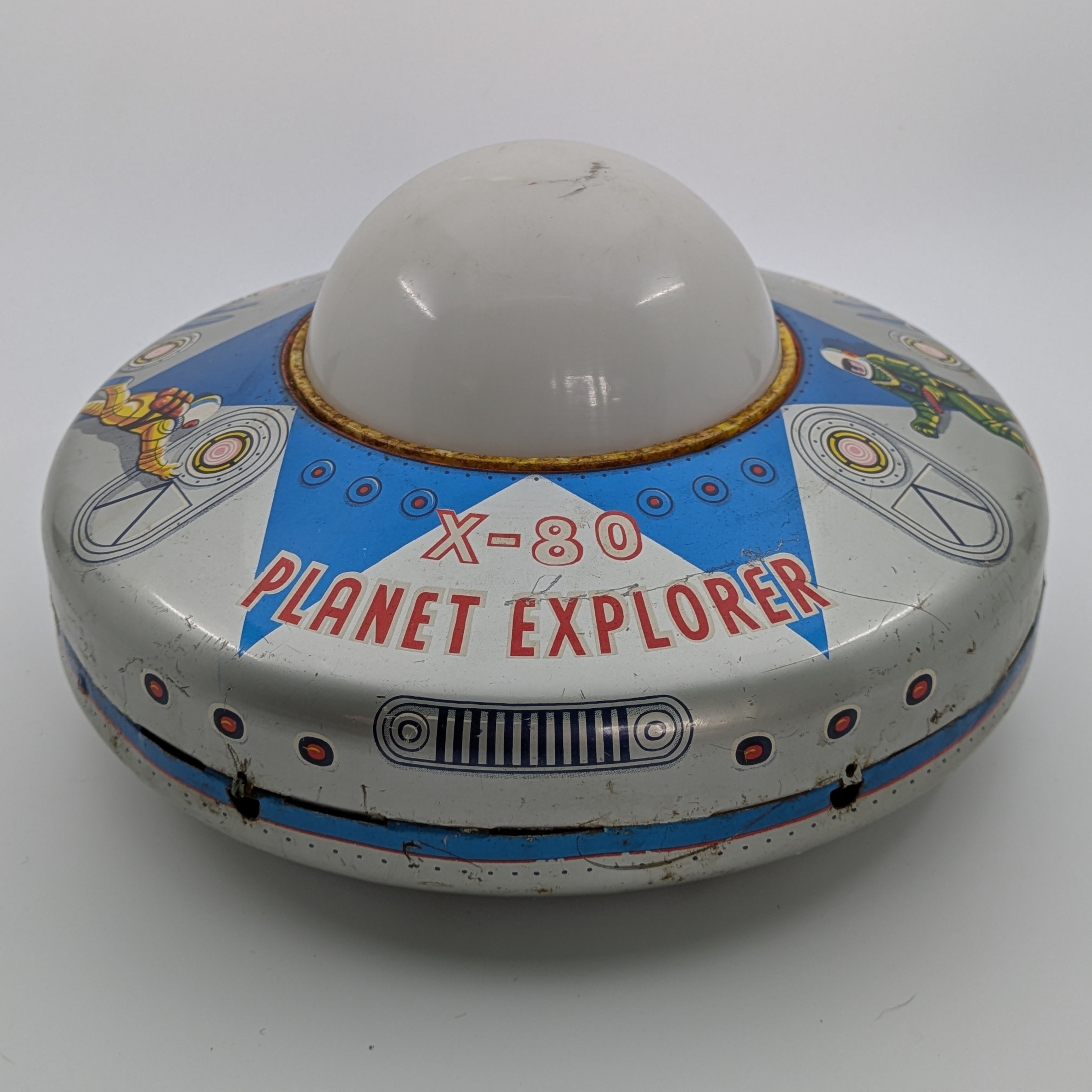Toy resembling a UFO with 'X-80 Planet Explorer' text on a white background