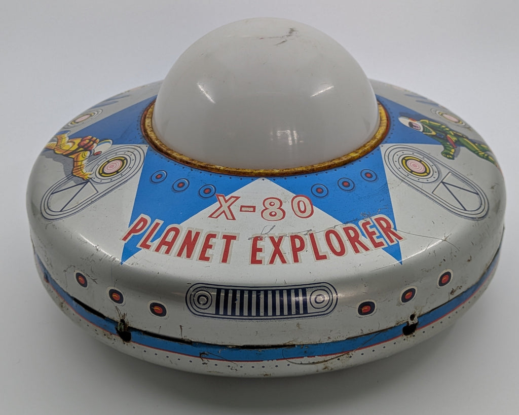 Toy resembling a UFO with 'X-80 Planet Explorer' text on a white background
