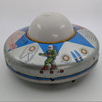 Vintage tin toy UFO with space-themed design on a white background