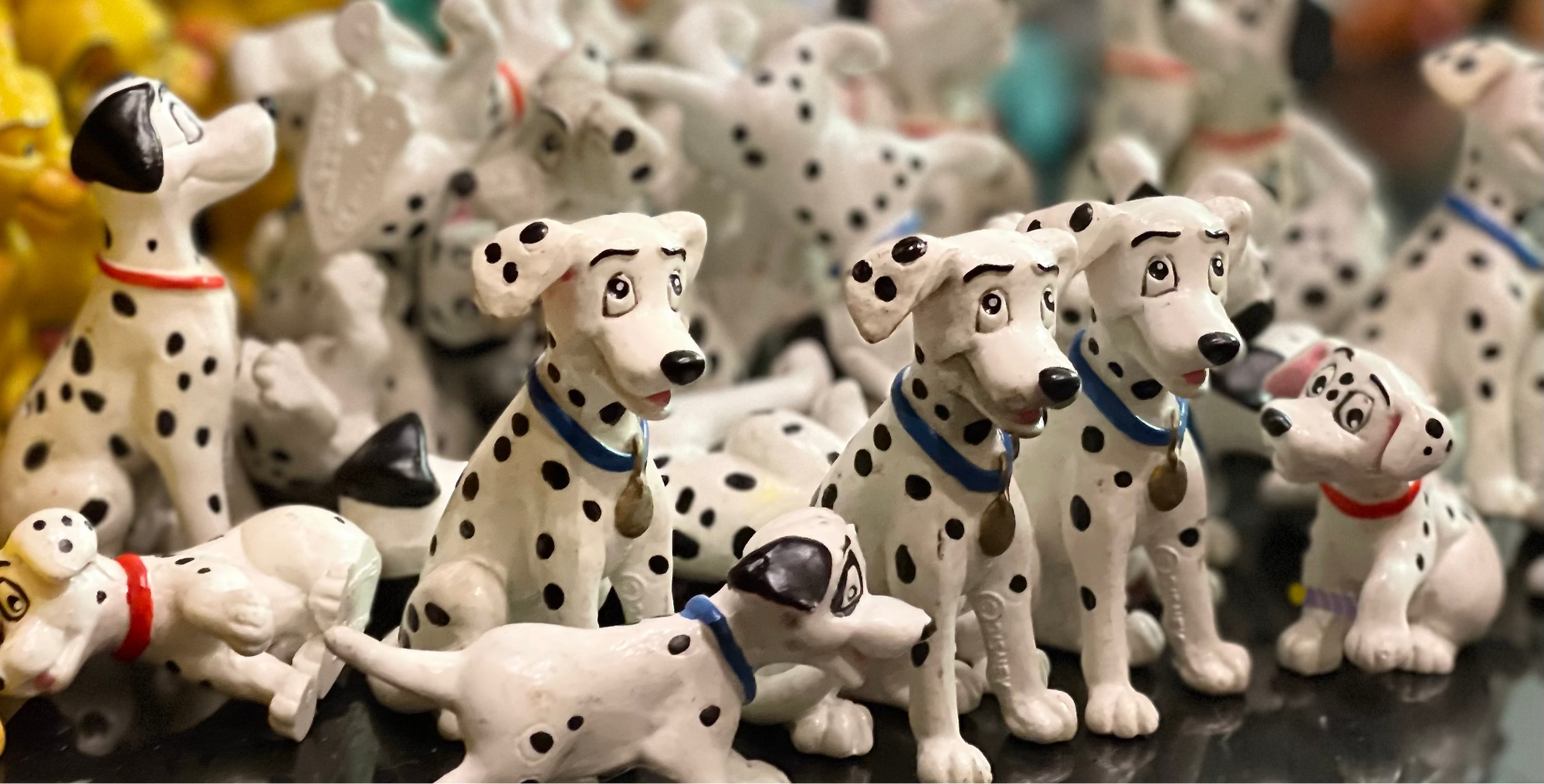 Collection of Dalmatian dog figurines on a reflective surface with a blurred background.