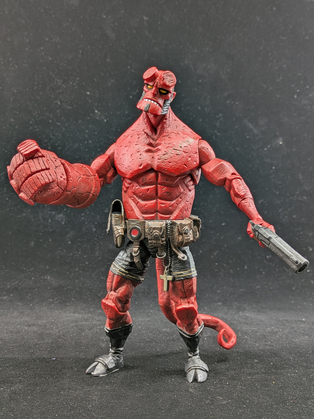 Red action figure with muscular build and weapon on a dark background