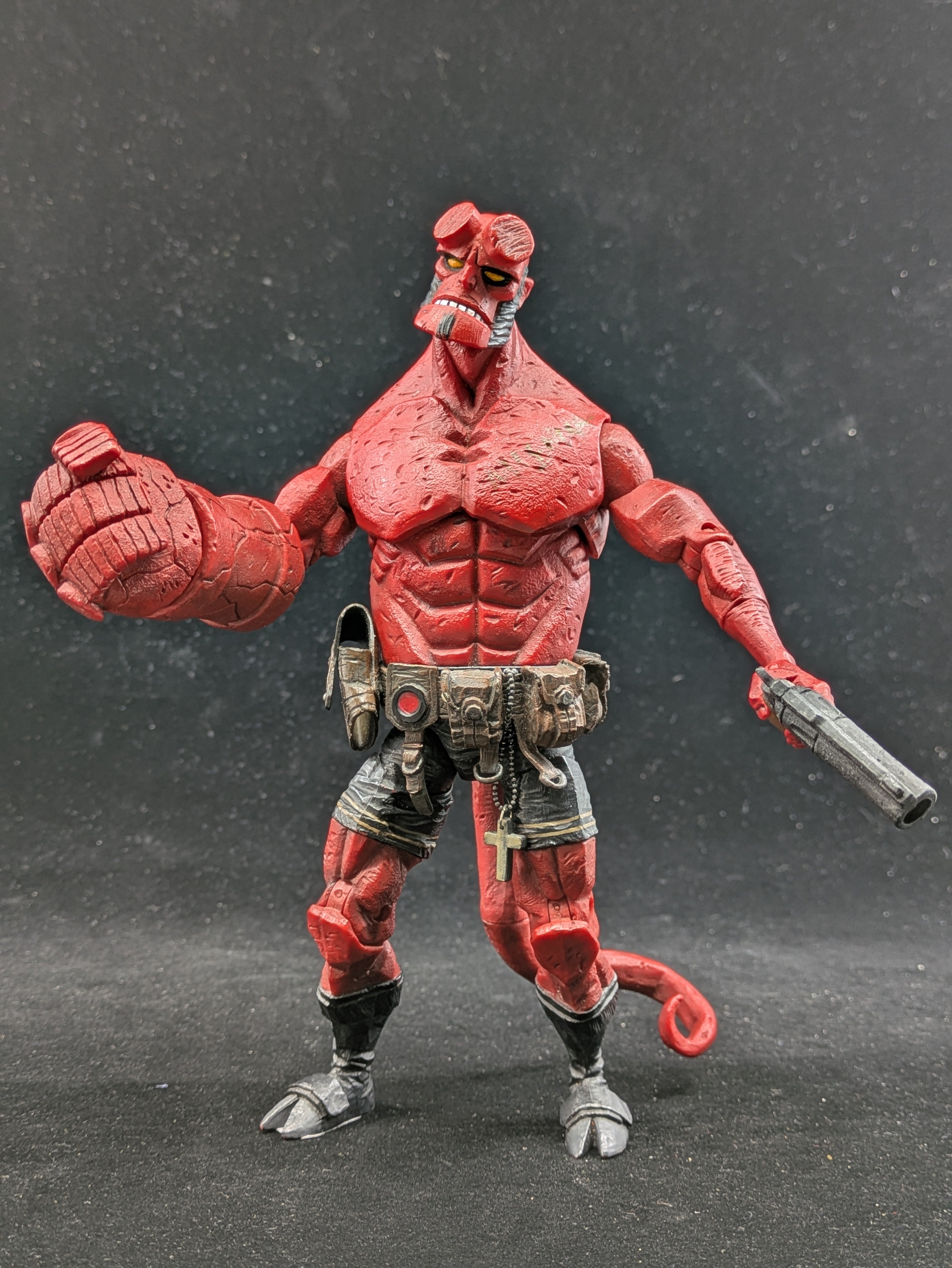 Red action figure with muscular build and weapon on a dark background