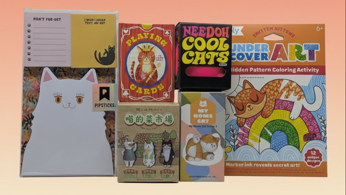 Collection of cat-themed products including a notepad, cards, and coloring books